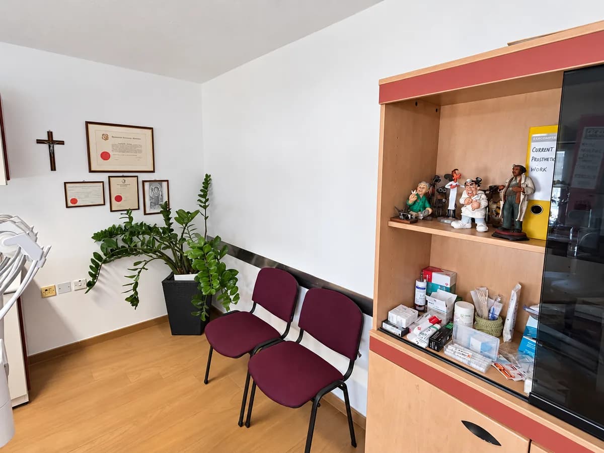 A corner of the clinic with plants, framed certificates and a display cabinet